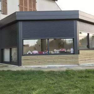 Extension d'un toit plat avec un bardage bois en clairevoie et en aluminium noir sablé à Caen